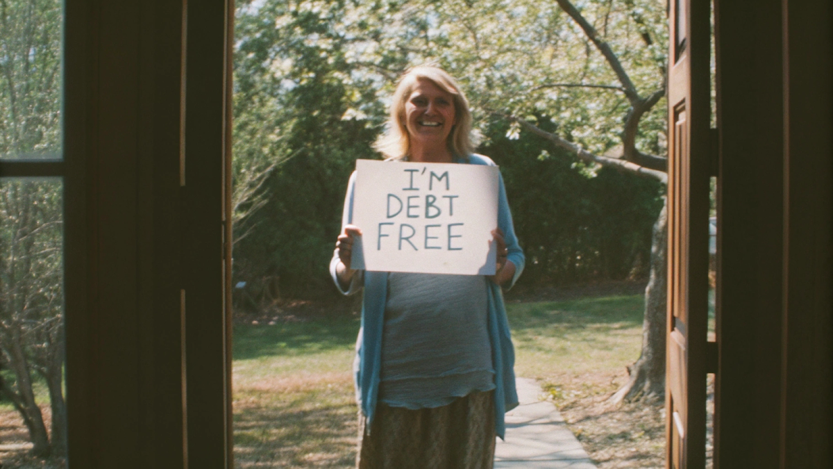 Senior holding I'm Debt Free sign